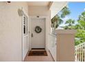 Charming entryway with a decorated white door, a welcome mat, and partial views of surrounding lush greenery and landscaping at 4244 Central Sarasota Pkwy # 726, Sarasota, FL 34238