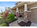 Inviting covered front porch with stone pillars, cozy seating, and colorful landscaping enhances curb appeal at 6356 Mighty Eagle Way, Sarasota, FL 34241