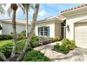 Charming home exterior with beautiful landscaping, palm trees, tile roof, and a cozy bench at 7124 Rue De Palisades # 21, Sarasota, FL 34238
