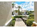 Pathway to a lovely home featuring well-maintained shrubs, garden bench and a clear view of the blue skies at 7124 Rue De Palisades # 21, Sarasota, FL 34238