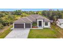Eye-level exterior showcasing this home's three-car garage, brick driveway, and a well-maintained front lawn at 7152 Bougainvillea St, Englewood, FL 34224