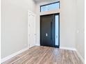Interior of a home's foyer with light gray walls, wood floors and a dark front door at 7152 Bougainvillea St, Englewood, FL 34224