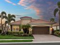 Inviting one-story home with tile roof, lush tropical landscaping, and brick paved driveway at sunset at 8911 Heritage Sound Dr, Bradenton, FL 34212