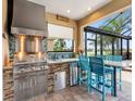 Outdoor kitchen with stainless steel grill and bar seating, perfect for entertaining at 8911 Heritage Sound Dr, Bradenton, FL 34212
