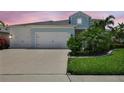 Charming two-story home with a three-car garage and lush landscaping set against a vivid sunset at 13918 Old Creek Ct, Parrish, FL 34219
