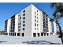 Exterior view of a modern condo building with screened lanais, parking and palm trees at 2045 Gulf Of Mexico Dr # M1-302, Longboat Key, FL 34228