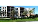 Exterior view of a bright condo building with palm trees, green grass, and ample parking at 2045 Gulf Of Mexico Dr # M1-302, Longboat Key, FL 34228