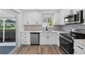 Modern kitchen with white cabinets, stainless steel appliances, and wood-look flooring at 2733 Riverbluff Pl # V57, Sarasota, FL 34231