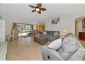 Spacious living room featuring tile flooring, a ceiling fan, a gray sofa set and sliding doors to the patio at 3718 61St E Dr, Bradenton, FL 34203