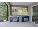 Covered outdoor kitchen featuring a grill, sink, mini-fridge, and stylish glass block window at 661 Foggy Morn Ln, Bradenton, FL 34212