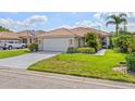 Charming single-story home with a tile roof, well-manicured lawn, and lush tropical landscaping at 6764 Hickory Hammock Cir, Bradenton, FL 34202