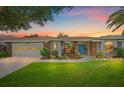 Charming home at sunset featuring a blue front door, well-manicured lawn, and colorful landscaping at 7984 Glenbrooke Ln, Sarasota, FL 34243