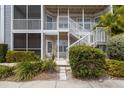 Close-up of condo entrance with white railings, door, and well-maintained landscaping at 850 S Tamiami Trl # 203, Sarasota, FL 34236