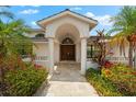 Grand entrance showcasing a large wooden door, columns, stone-tile walkway, and lush landscaping at 868 Siesta Key Cir, Sarasota, FL 34242