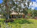 Beautiful brick home with lush landscaping and a large tree shading the front yard at 911 Cimarron Cir, Bradenton, FL 34209