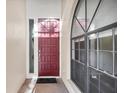 Elegant entryway featuring a paneled red front door, sidelight, and decorative window at 4517 Las Brisas Ln, Sarasota, FL 34238