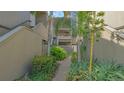 Exterior view of a condo building with landscaped walkway, tropical plants, and stairs to upper units at 107 Woodland Pl # 107, Osprey, FL 34229