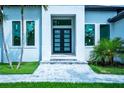 Contemporary home featuring a modern glass front door, with tiled entrance and lush landscaping at 117 Marker Rd, Rotonda West, FL 33947