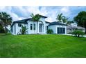 Beautiful modern home with lush lawn, palm trees, dark roof, and a two-car garage at 117 Marker Rd, Rotonda West, FL 33947