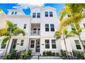 Beautiful three-story townhouse featuring a quaint balcony, complemented by lush palm trees and an inviting entrance at 2408 Ezzell Ct, Sarasota, FL 34237