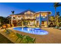 Luxurious home featuring a large, illuminated pool and hot tub with ample seating and a spacious outdoor entertainment area at 26 Sandy Hook S Rd, Sarasota, FL 34242