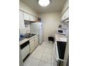 Efficient kitchen layout with white cabinets, appliances, and tile flooring for easy maintenance at 2624 Hidden Lake Dr N # C, Sarasota, FL 34237