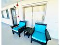 Outdoor patio featuring two chairs with blue cushions and a small table with sliding door access at 3320 Gulf Of Mexico Dr # 307C, Longboat Key, FL 34228