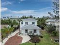 A beautifully landscaped front yard leads up to this lovely two-story home with eye-catching gray roof and white siding at 580 Russell St, Longboat Key, FL 34228