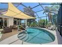 Screened-in pool area featuring a sunshade, patio furniture, and lush landscaping at 6539 Flycatcher Ln, Lakewood Ranch, FL 34202