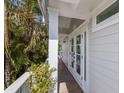 Inviting entrance with french doors, a covered porch, and lush tropical landscaping surrounding the doorway at 799 Jacaranda Rd, Anna Maria, FL 34216