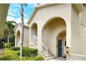 Close-up of a beige condo building entrance showcasing arched entryways, white railings, and verdant landscaping at 8315 Glenrose Way # 1421, Sarasota, FL 34238