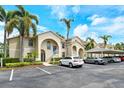 Two-story condo with beige facade, blue doors, mature palms, manicured hedges and convenient covered parking spaces at 8315 Glenrose Way # 1421, Sarasota, FL 34238