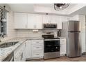 Modern kitchen with stainless steel appliances, white cabinets, and granite countertops at 104 Capri Isles Blvd # 207, Venice, FL 34292