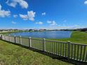 Scenic view of a tranquil pond surrounded by lush green grass and a white picket fence, perfect for relaxation at 13156 Merlot Sunstone Cv, Parrish, FL 34219