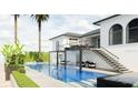 A Luxurious pool with waterfall feature and palm trees, adjacent to an outdoor dining area on the upper level at 1384 Harbor Dr, Sarasota, FL 34239