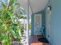 Charming porch with tropical landscaping, blue siding, and a comfortable chair at 170 Roosevelt Dr # 2, Sarasota, FL 34236