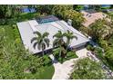 An overhead view of a home featuring a screened pool, tile roof, palm trees and verdant landscaping at 1780 Pine Harrier Cir, Sarasota, FL 34231