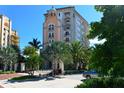 Elegant condo building exterior surrounded by lush landscaping and mature palm trees on a sunny day at 420 Golden Gate Pt # 200A, Sarasota, FL 34236
