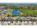 Aerial view of a residential area, featuring a serene pond surrounded by lush greenery, and neatly arranged houses at 5033 Brickwood Rise Dr, Wimauma, FL 33598