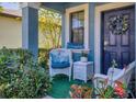 Inviting front porch with cozy seating, decorative pillows, vibrant plants, and a charming wreath on the door at 5033 Brickwood Rise Dr, Wimauma, FL 33598