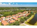 Aerial view of the community showcasing the orange roofs, lush greenery, and serene pond at 6462 Draw Ln # 72, Sarasota, FL 34238