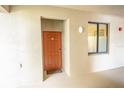 Front door entrance with orange door, welcome mat, and sidelight window at 7005 River Hammock Dr # 204, Bradenton, FL 34212