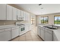 Bright kitchen with white cabinets, tile floors, a gas range, and picturesque backyard view at 8118 Stirling Falls Cir, Sarasota, FL 34243