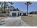Inviting single-story home featuring a gray garage door and palm trees in a well-manicured yard at 904 Winter Garden Dr, Sarasota, FL 34243