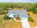 Aerial shot of a single-story home with landscaping, long driveway, surrounded by trees and an open field at 10001 289Th E St, Myakka City, FL 34251