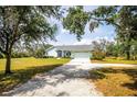 Exterior view of this charming home with a long driveway, lush lawn and mature trees offering plenty of shade at 10001 289Th E St, Myakka City, FL 34251