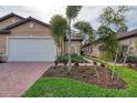 Charming single-Gathering home with a well-manicured lawn, brick driveway, and white garage door at 12091 Firewheel Pl, Venice, FL 34293