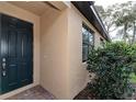 Inviting home exterior showcasing a dark front door, window, and manicured landscaping at 12091 Firewheel Pl, Venice, FL 34293