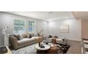 Bright living room featuring neutral tones, a tufted sofa, and large windows for natural light at 1227 Porpoise Rd, Venice, FL 34293