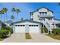 Exterior of a light-gray two-story home, featuring a two-car garage, palm trees, and a bright-blue sky at 1311 Siesta Bayside Dr # 1311-A, Sarasota, FL 34242